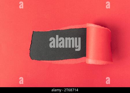 Hole in red paper on black background. Mockup. Stock Photo
