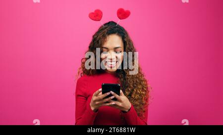 Beautiful young woman texts and smiles, Valentines Day, dating app Stock Photo
