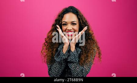 Cute young woman poses with hands under chin, dressed up for Valentine's Day Stock Photo