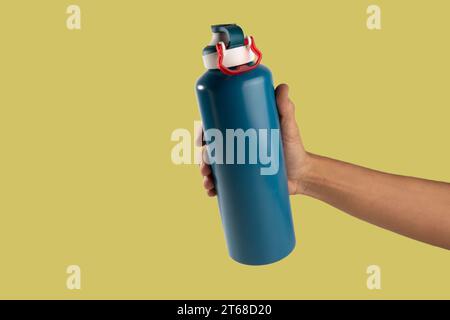 Black male holding thermo bottle canteen on light yellow background Stock Photo