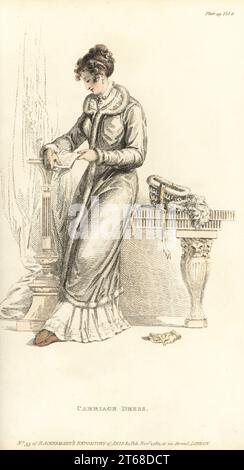 Regency woman reading a letter wearing a carriage dress. Morning dress in India muslin with needlework border a la Grecque, French wrapping coat of grey silk, trimmed with swansdown. Beehive hat with ostrich feathers on table. Plate 29, November 1 1811. Handcoloured copperplate engraving by Thomas Uwins from Rudolph Ackermann's Repository of Arts, London. Stock Photo