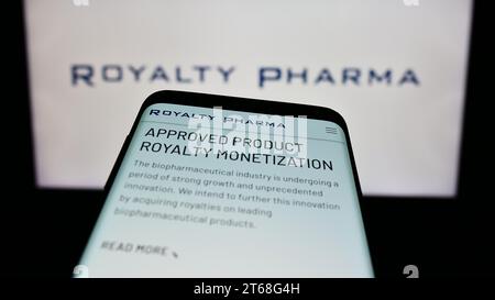 Smartphone with website of US biopharmaceutical royalties company Royalty Pharma in front of business logo. Focus on top-left of phone display. Stock Photo
