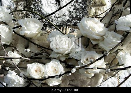 Partial view of a floral arrangement of white roses, carnations and willow sticks with buds. Floral art. Stock Photo