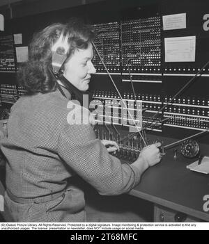 Telephony in the 1950s. Woman working at a telephone switchboard as it's operatos. A telephone communication system that was manually operated where the incoming calls were forwarded and redirected to the another telephone number by the operator, in this case locally within the building serving a company or an organization with many internal telephone lines. The switchboard operator could take messages, put you on hold if the line was busy. Sweden 1953. Kristoffersson ref BM99-7 Stock Photo