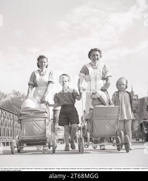 For a walk in the 1940s. Two women in nurses uniform are out walking pushing prams in front of them in. Stockholm   Sweden may 1940 Kristoffersson ref 133-6 Stock Photo