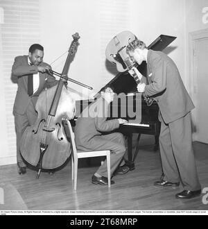 An unknown musical trio where the bassist and guitarist seem less than happy with the pianist, and threaten him with their respective musical instruments. Sweden 1953. Kristoffersson ref BL43-12 Stock Photo