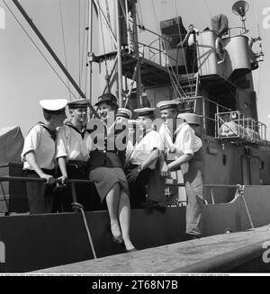 In the 1950s. A young woman in uniform at the dock surrounded by sailors from the crew of the ship Sturkö, which belongs to the Swedish Navy. The picture was taken in Visby on the island of Gotland, Sweden in 1959. Kristoffersson ref CG40-5 Stock Photo