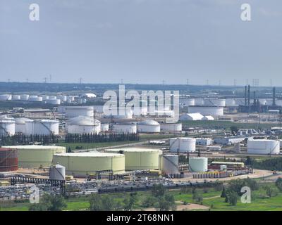 An aerial view of a large lot with oil tanks surrounded by lush green grass and trees Stock Photo