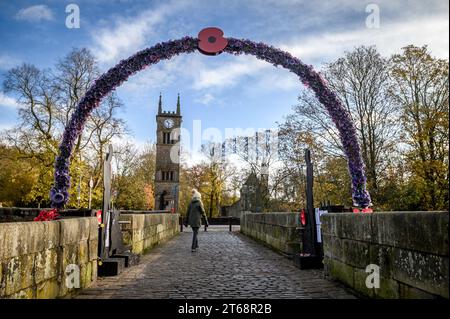 Bolton, UK. 9th November 2023. Locals from the village of Rigley, Bolton, have decorated the ancient Rigley Old Bridge over the River Irwell with a waterfall of red poppies and an arch of purple poppies as part of their annual Remembrance commemorations. Credit: Paul Heyes/Alamy Live News Stock Photo