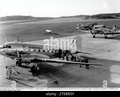 1950s airport. People are arriving by a Swedish airlines Douglas DC-3 plane to Bromma airport in Stockholm in the 1950s. Stock Photo
