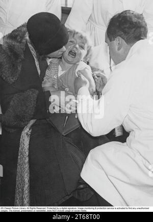 Vaccines in the 1940s. A doctor gives a young boy a vaccine shot in 1940. Vaccines are given against diseases such as: Tetanus, Whooping Cough, Polio, Measles, Rubella etc. Stock Photo