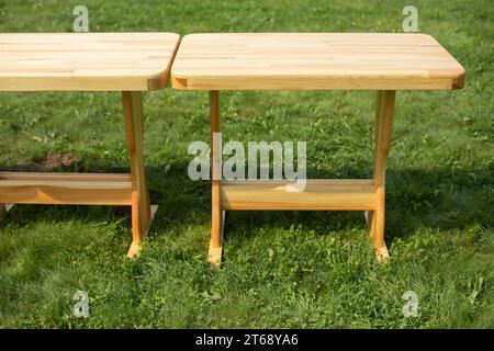 Wooden table on a green lawn. Wooden furniture in the park. Empty tables. A place to relax in the summer. Stock Photo