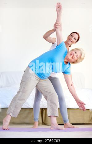 Senior health and exercise. Full-length portrait of an elderly woman doing stretches with her fitness trainer. Stock Photo