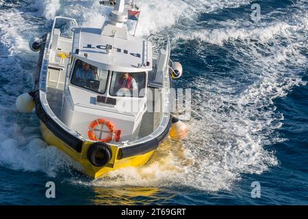 Pilot boat in the Caibbean Sea being positioned to bring the harbor pilot onto a cruise ship off the coast of Phillipsburg, St. Martin Stock Photo