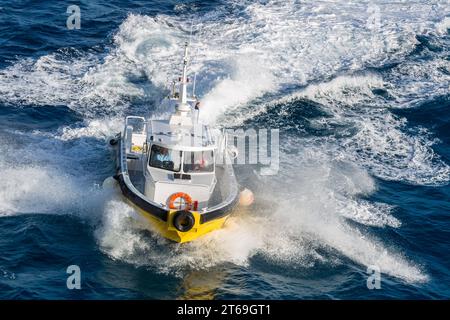 Pilot boat in the Caibbean Sea being positioned to bring the harbor pilot onto a cruise ship off the coast of Phillipsburg, St. Martin Stock Photo