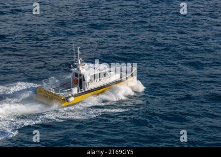 Pilot boat in the Caibbean Sea being positioned to bring the harbor pilot onto a cruise ship off the coast of Phillipsburg, St. Martin Stock Photo