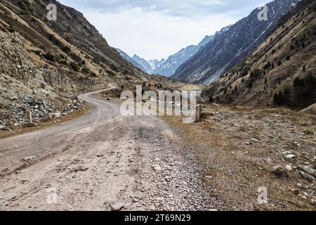 Rocky gravel road in the hillside leading into the mountains, bottom view. Early spring in nature Stock Photo