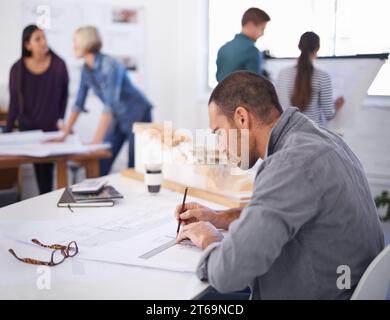 Working hard to reach that deadline. a handsome architect working at his desk. Stock Photo