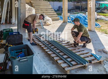 American men preparing metal studs while volunteering to help build Grace Language School and Baan Athitaan Church building in Chiang Rai, Thailand Stock Photo