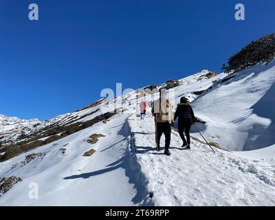 A group of people skiing down a snow-covered mountain path, enjoying the winter scenery Stock Photo