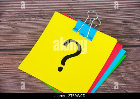 Question mark on yellow notepad with wooden desk background. Motivational concept. Stock Photo