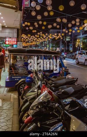 Motor scooters and bike taxis line the side of the downtown street in Chiang Rai, Thailand Stock Photo