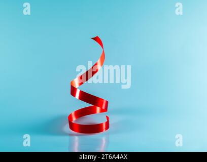 Twisted glossy red ribbon isolated on a blue background, vertical Stock Photo