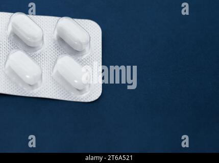 White blister pills on dark blue background. Stock Photo