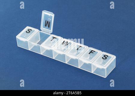 Pill organizer, pill box on blue background close-up. Organization of taking pills of the day. Stock Photo