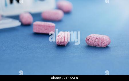 Conceptual image of a pill organizer with pills scattered on a blue table. Stock Photo