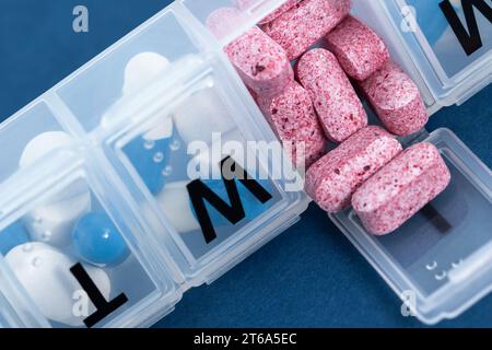 Daily pill box, pill organizer with variety of pills and supplement. Weekly pill organizer closeup. Stock Photo