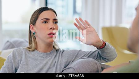 Woman, fight and divorce on sofa in home with discussion, talking or upset with spouse for cheating. Female person, wife and gesture in stop for lies Stock Photo
