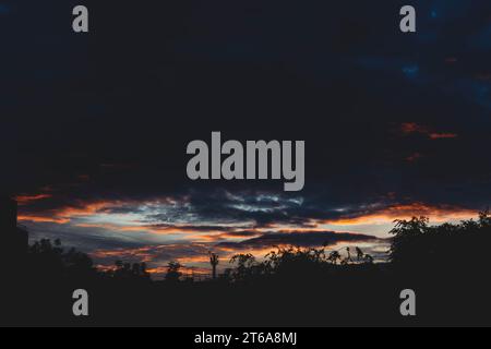 Beautiful sunset sky in dark shades. The sunset breaks through the black clouds.. Stock Photo