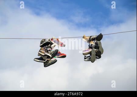 Sports shoes hanging from an overhead wire Stock Photo