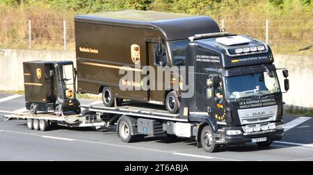 UPS Electric parcel van towing trailer carrying miniature UPS cargo cart loaded on DAF flat platform recovery delivery lorry truck M25 road England UK Stock Photo