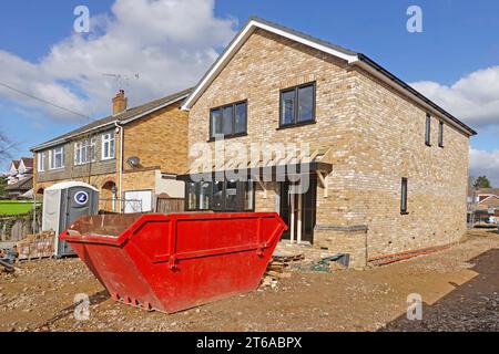 Series stages of work in progress pics detached house infill plot window frames fixed front canopy rafters & rubbish skip for clearing up England UK Stock Photo