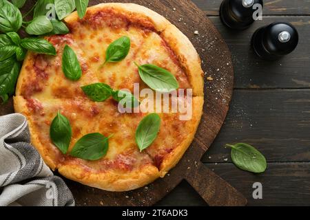 Margarita pizza. Traditional neapolitan margarita pizza and cooking ingredients tomatoes basil on wooden table backgrounds. Italian Traditional food. Stock Photo