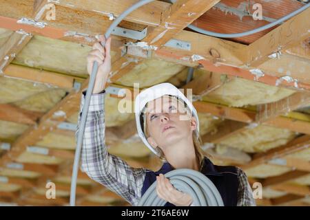female electrician installing ventilation in ceiling Stock Photo