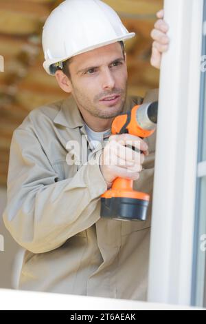 builder using cordless drill to install windows Stock Photo