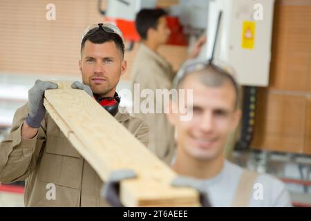 construction workers carrying boards at construction site Stock Photo