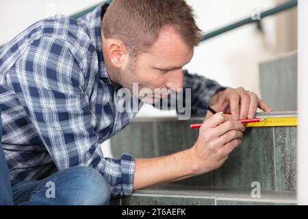young worker using tape measure for measuring staircases Stock Photo