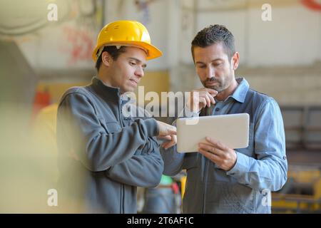 contemplative manual workers looking at digital tablet Stock Photo