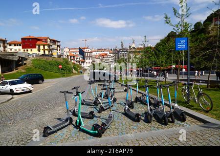 Electric scooters parked at sharing point, Igreja dos Congregados church and city hall tower in distance, Ribeira, Porto / Oporto, Portugal Stock Photo