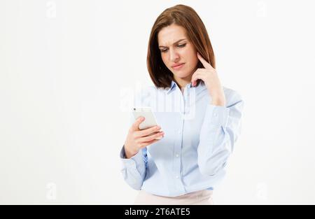 Upset woman holding a cellphone. Angry young businesswoman reading bad news on her cell phone. Isolated on white background. Stock Photo
