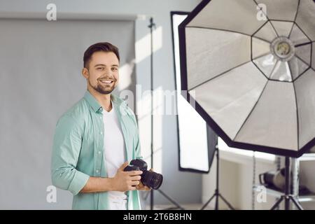 Portrait of handsome photographer posing with his camera in office Stock Photo