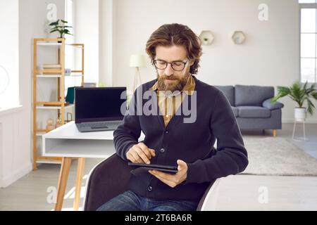 Serious businessman uses some applications to work while working on digital tablet. Stock Photo