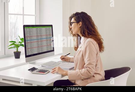 Businesswoman analyzing financial data on computer screen in office Stock Photo