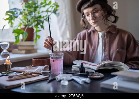 Animated artist-illustrator in glasses, vintage clothes, beret drawing animation painting in studio Stock Photo