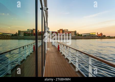 Hotel and Conferencecenter by Upper Mississippi on calm evening in Dubuque Iowa reflected in windows of departing river cruise Stock Photo