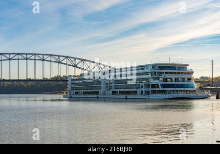 Dubuque, IA - 17 October 2023: Viking Mississippi river cruise boat docked by modern road bridge on Mississippi river in Iowa Stock Photo